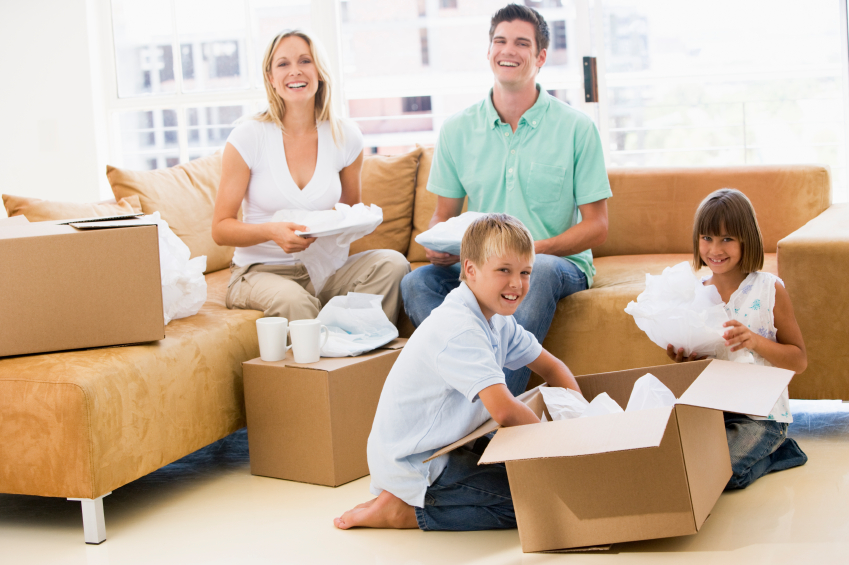 Family unpacking boxes in new home smiling